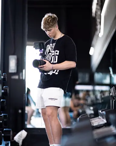Malakai checking footage on a camera in the middle of a gym