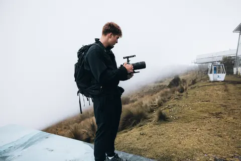 Malakai filming on a foggy hillside by a cable car