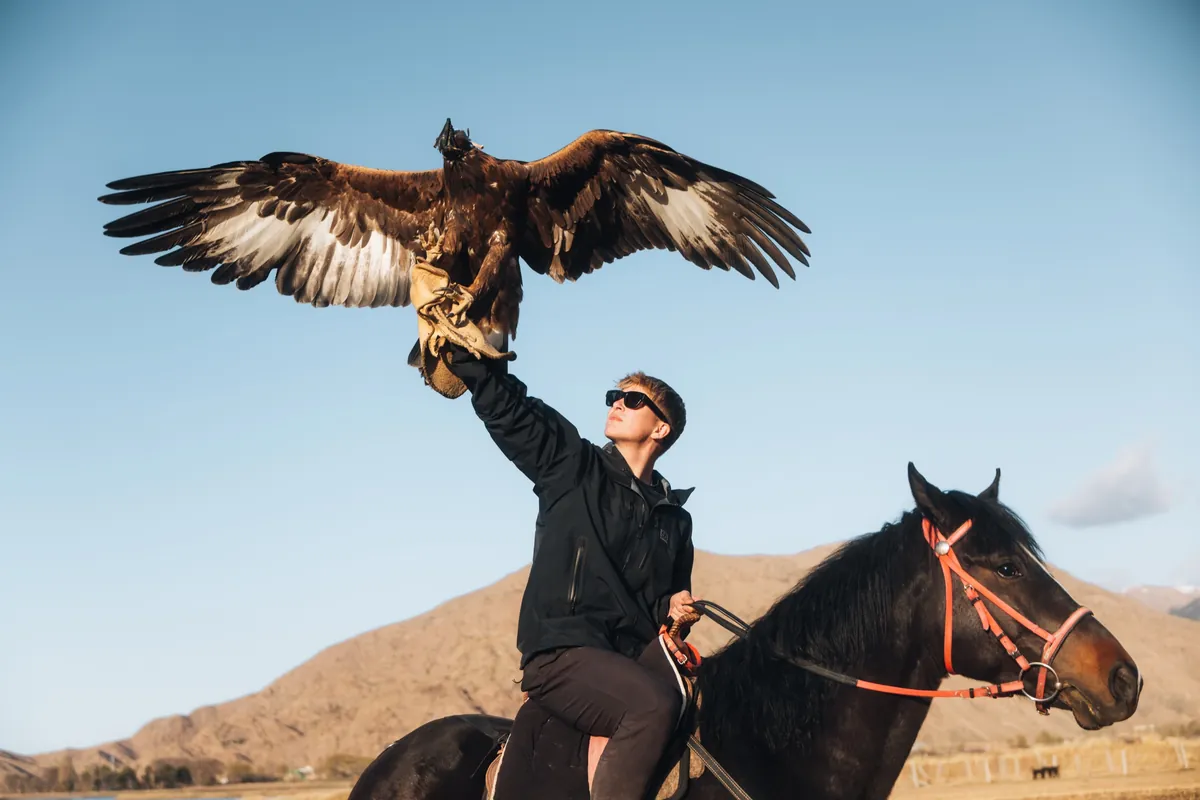 Malakai on horseback with an eagle landing on his arm, wings spread