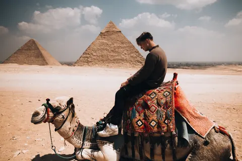 Malakai on a decorated camel in front of the pyramids