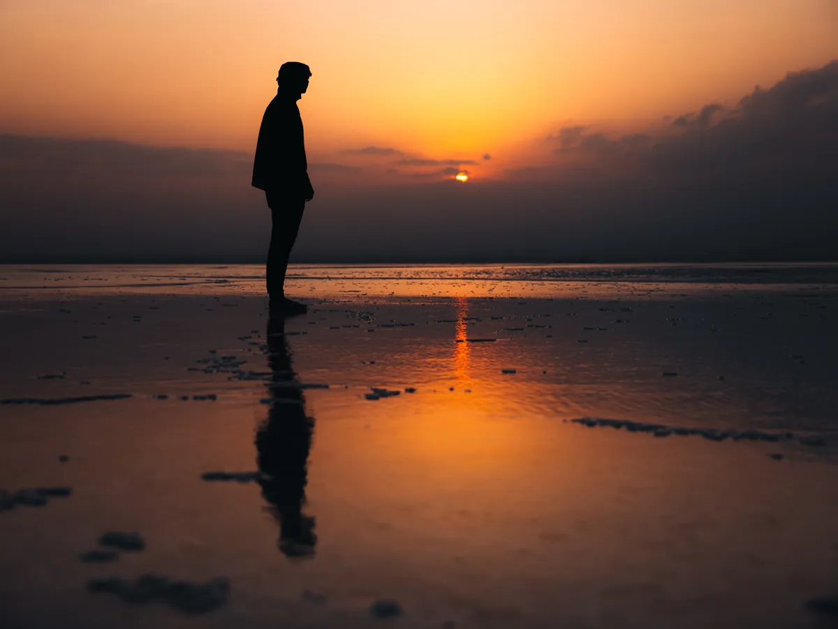 Malakai's silhouette and reflection on the Danakil salt flats at sunset