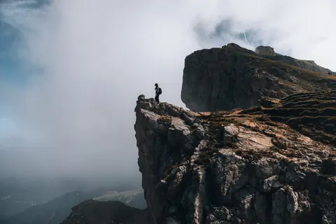 Malakai standing on the edge of a cliff above the clouds