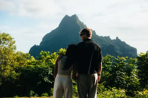 Malakai and Maddie side by side, a jagged green mountain ahead of them