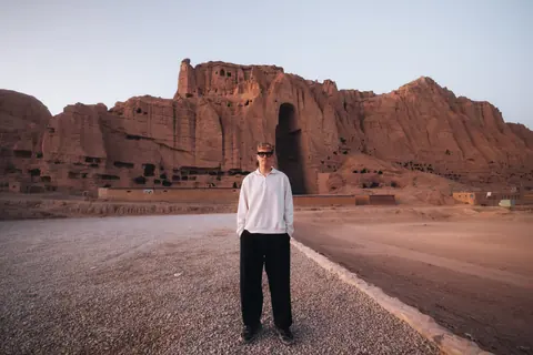 Malakai standing on a road below tall sandstone cliffs
