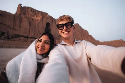 Malakai and Maddie smiling in a selfie beneath the cliffs of Bamiyan