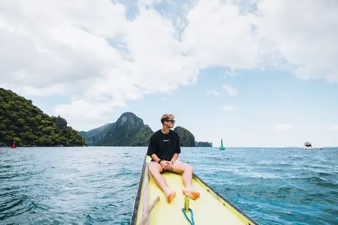Malakai riding at the front of a small boat on clear blue water