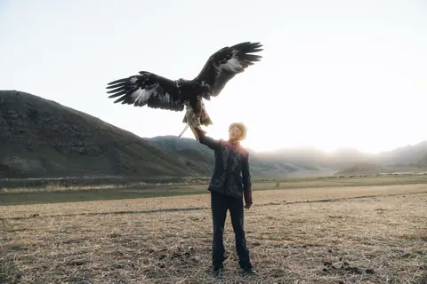 Malakai holding up a golden eagle with its wings spread