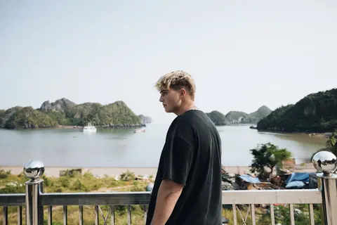 Malakai at a railing above a bay of green limestone islands
