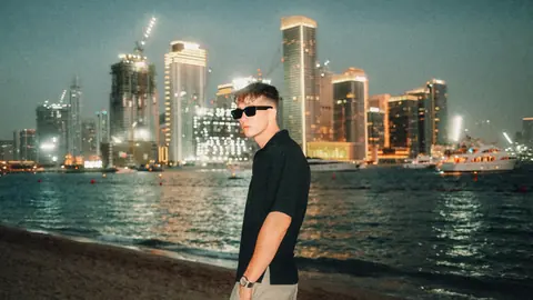 Malakai at dusk with lit towers behind him