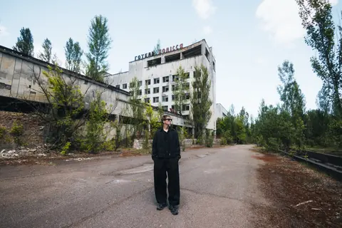 Malakai standing on an empty street in front of an abandoned hotel
