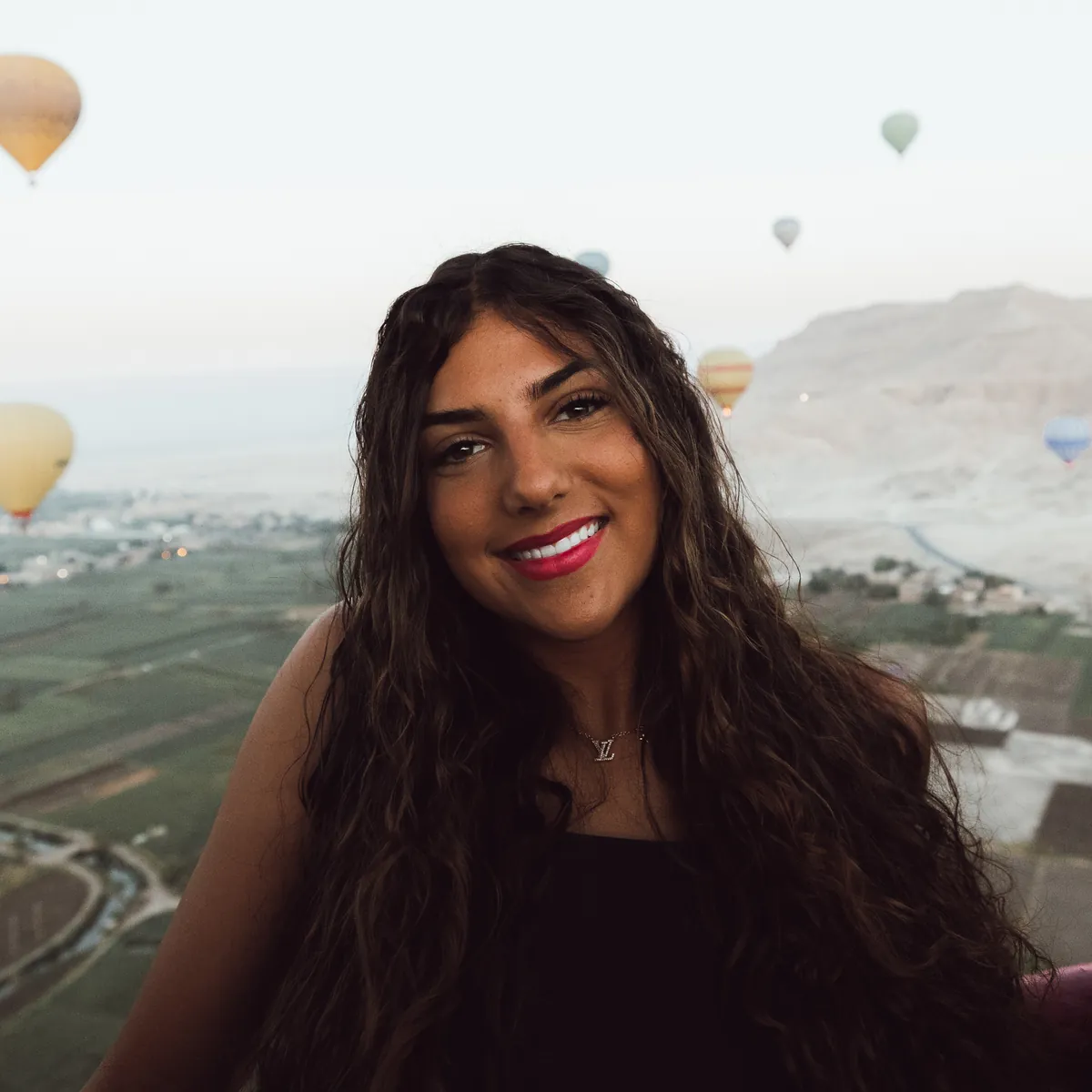 Maddie smiling into the camera from a hot-air balloon at sunrise