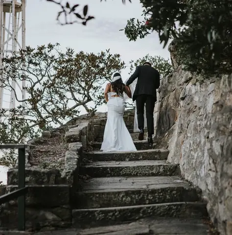 Malakai and Maddie walking up old stone steps in their wedding clothes