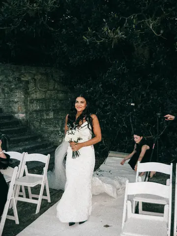Maddie in her dress walking between rows of white chairs