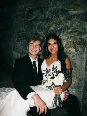 Flash photo of Malakai and Maddie sitting together, her bouquet in her lap